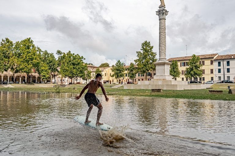 Ragazzo fa surf in Piazza Ariostea allagata. Foto Luca Pasqualini